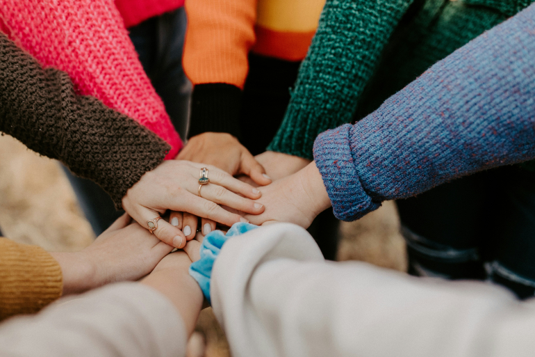 lots of hands stacked in middle connoting connection