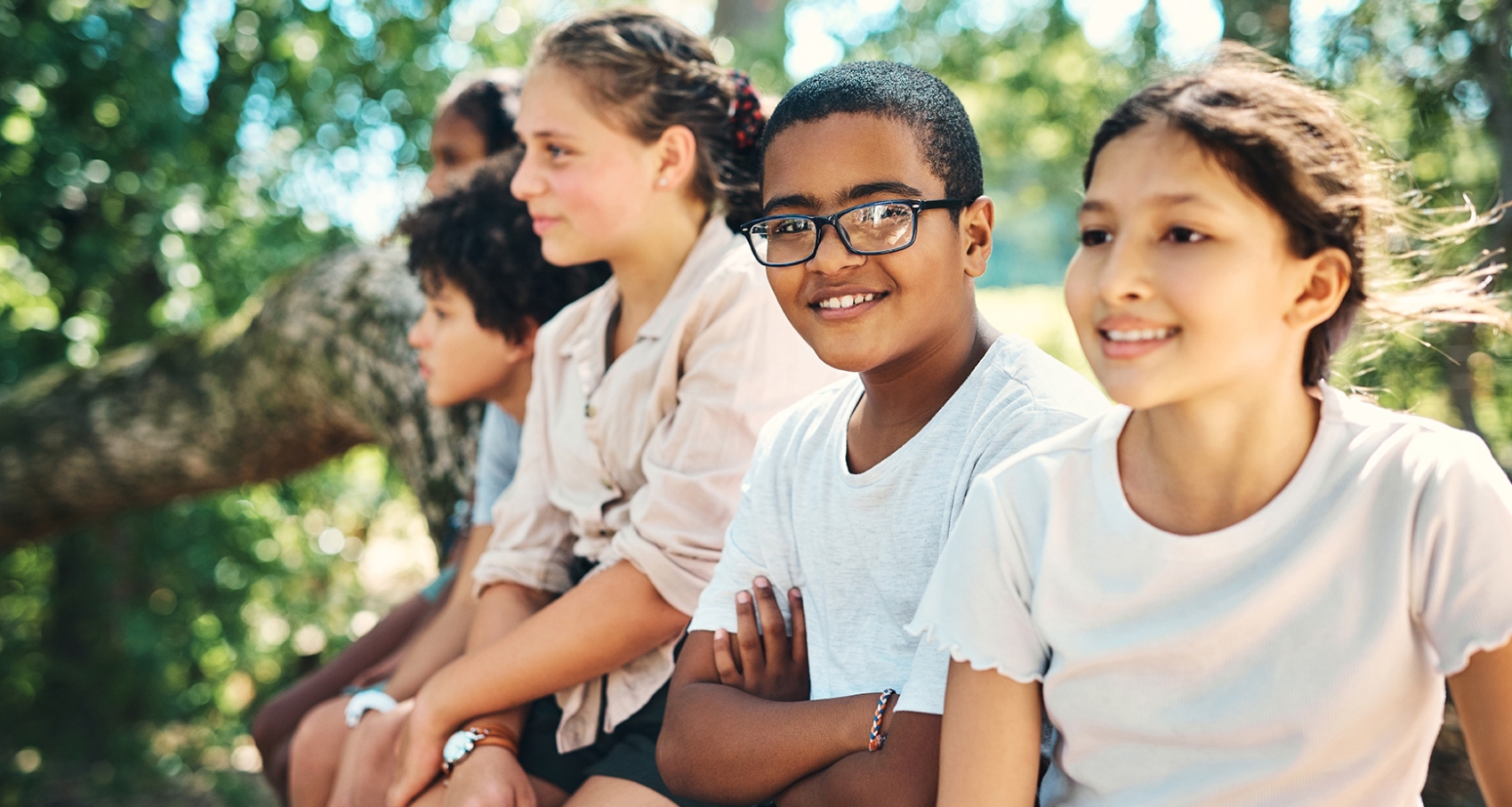 Children sit on log in the sun 